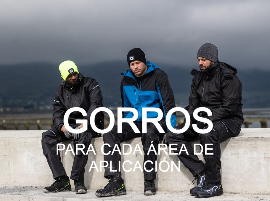 Imagen de tres hombres con diferente ropa de trabajo. Los tres llevan sombreros en la cabeza y están sentados en un muro de hormigón. Al fondo se puede ver una montaña cubierta de nubes y una niebla gris. Se proporciona un enlace a nuestra selección de sombreros.