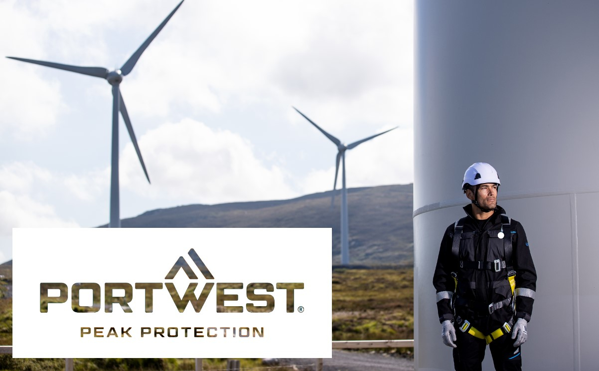 Un trabajador que lleva equipo completo de protección contra caídas se encuentra junto a una turbina eólica. Al fondo se pueden ver más turbinas eólicas. En primer plano se muestra el logotipo de la empresa Portwest con el lema "Peak Protection". Se proporciona un enlace que conduce a nuestra protección contra caídas.