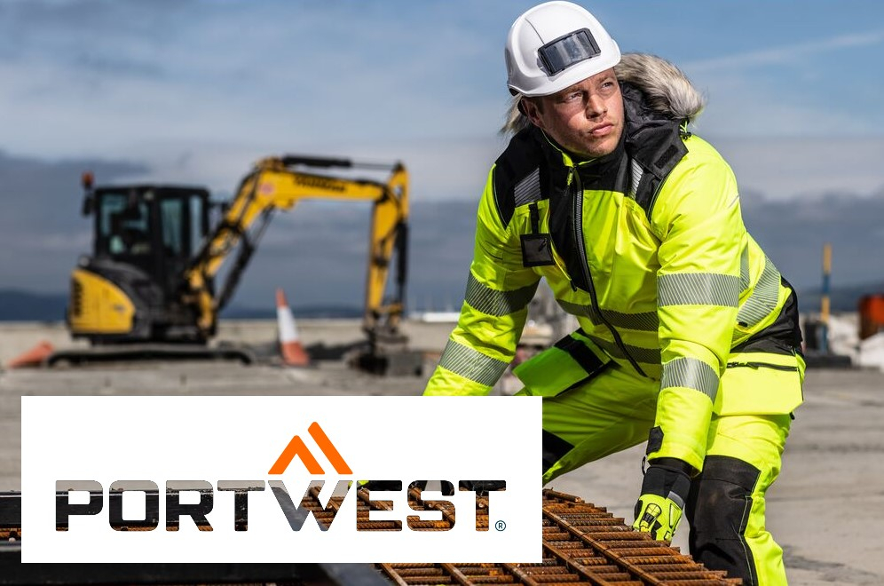 Trabajador con ropa de invierno amarilla y casco blanco levantando una reja de hierro. Al fondo se puede ver una excavadora, una cadena montañosa y un cielo azul. En la parte inferior izquierda de la imagen se ve el logotipo de Portwest sobre un fondo blanco. Se proporciona un enlace a nuestras chaquetas de invierno.