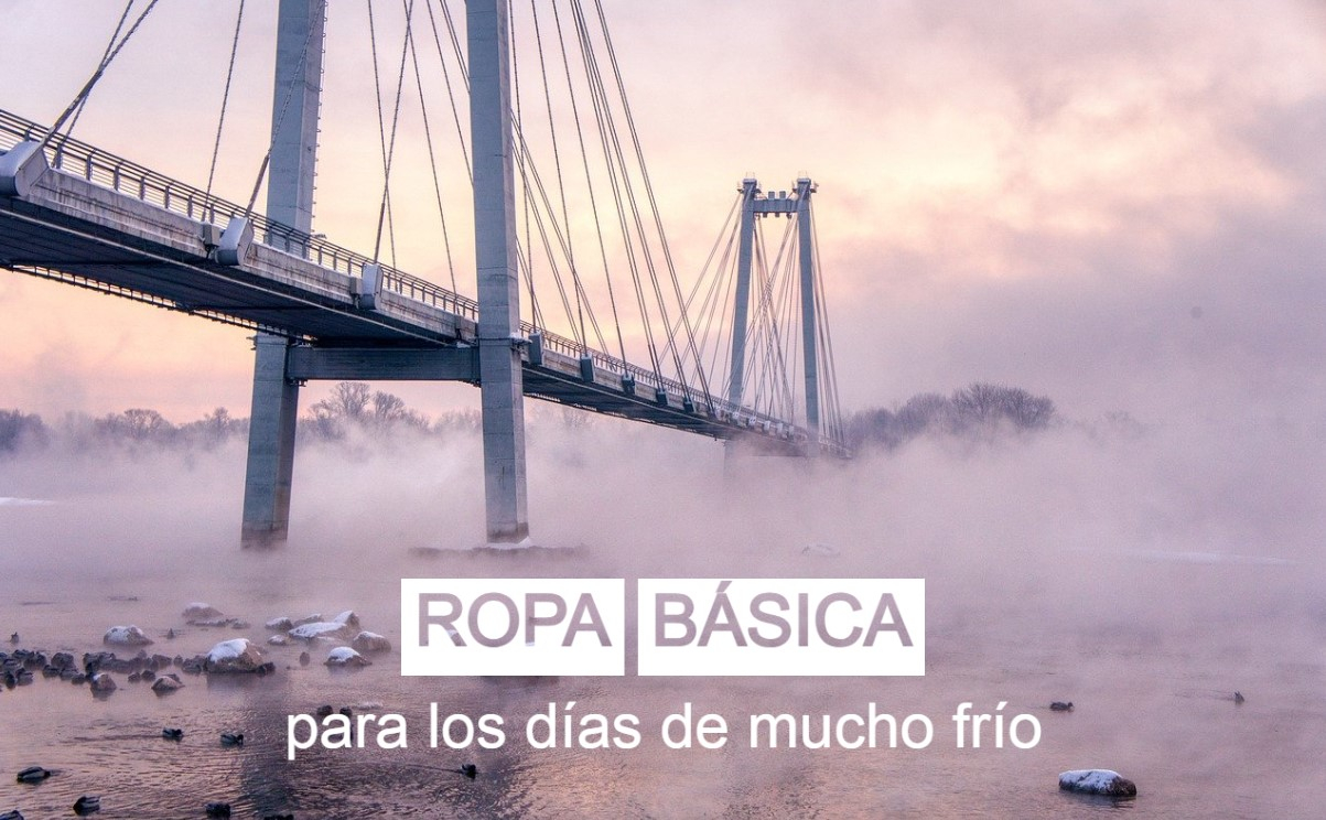 Un puente colgante que cruza un río helado y brumoso, capturado al amanecer. Sobre la imagen aparece escrito en grandes letras blancas el texto “Ropa interior para días de trabajo extremadamente fríos”. La escena transmite una atmósfera invernal y helada. Se proporciona un enlace a nuestra ropa interior.