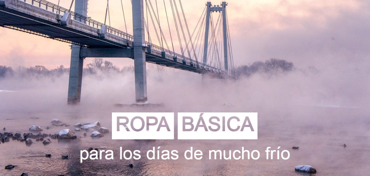 Un puente colgante que cruza un río helado y brumoso, capturado al amanecer. Sobre la imagen aparece escrito en grandes letras blancas el texto “Ropa interior para días de trabajo extremadamente fríos”. La escena transmite una atmósfera invernal y helada.