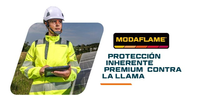 Mujer con ropa protectora amarilla de alta visibilidad y casco blanco sosteniendo una tableta y parada frente a un prado y paneles solares. Al lado está el logotipo de Modaflame y el título Premium Inherent Flame Retardancy. Se proporciona un enlace a la colección Modaflame.